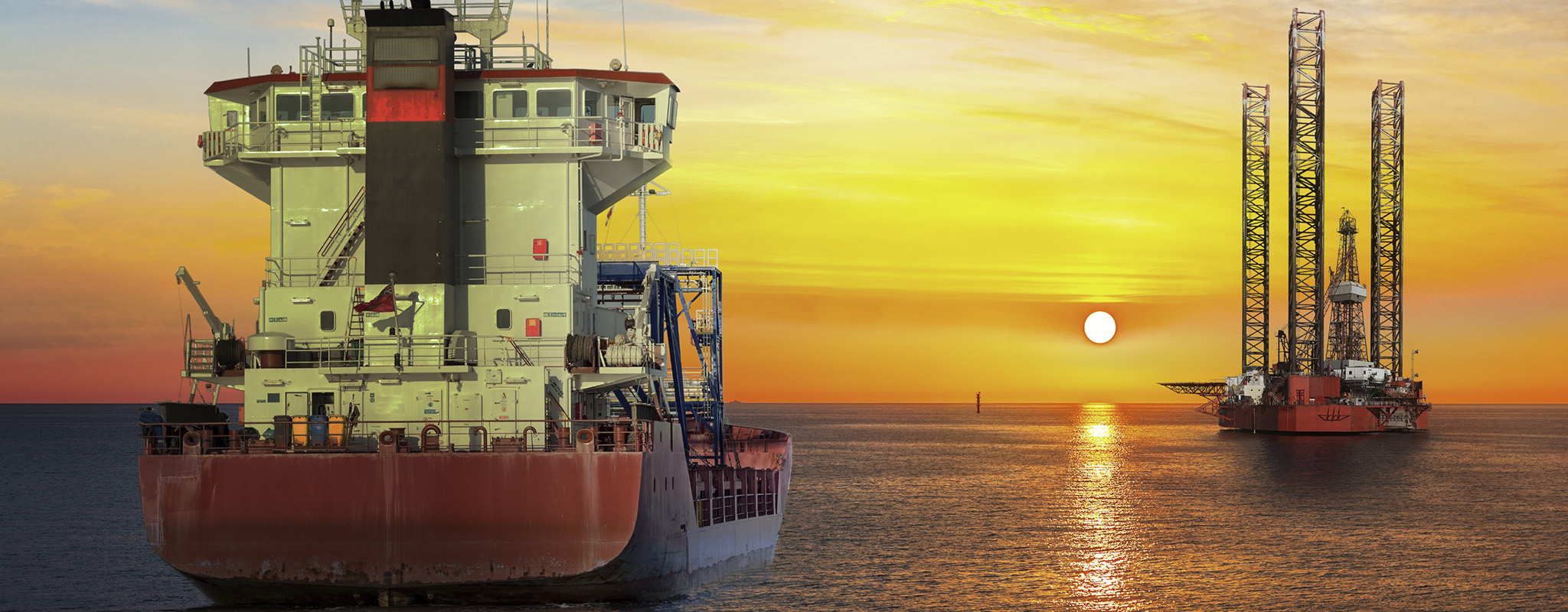 Tanker ship and oil platform offshore at sunset